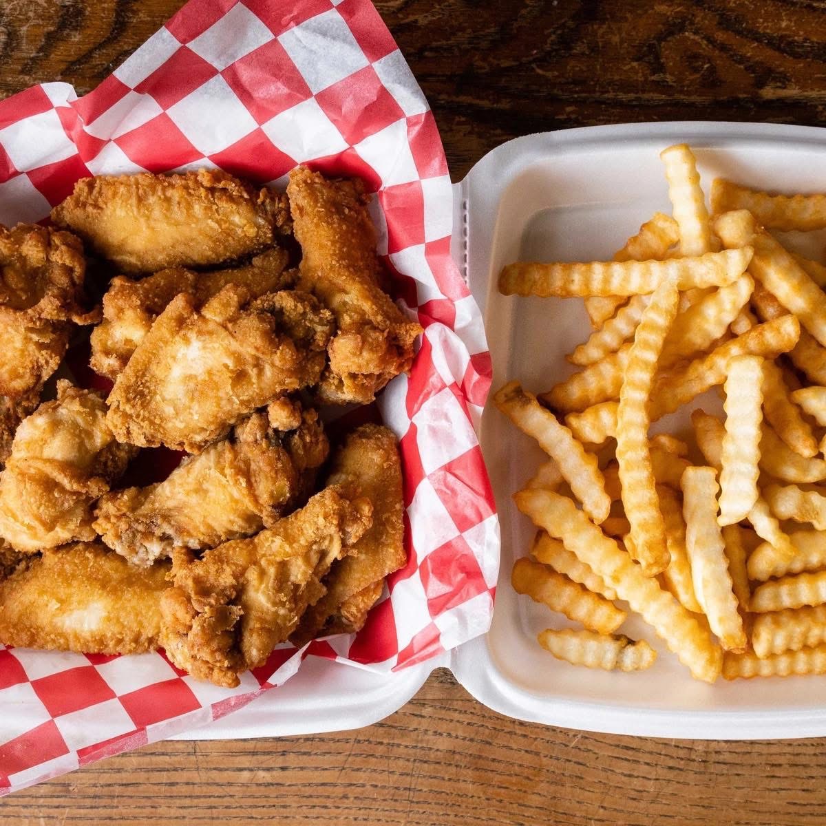 Crispy fried wings with crinkle-cut fries on checkered paper