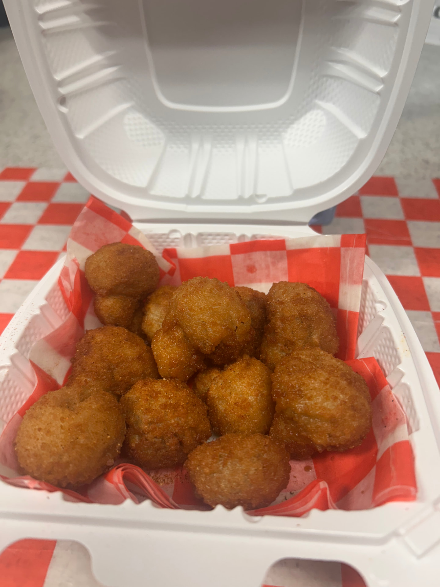 Batter-fried mushrooms in a takeout box on checkered paper
