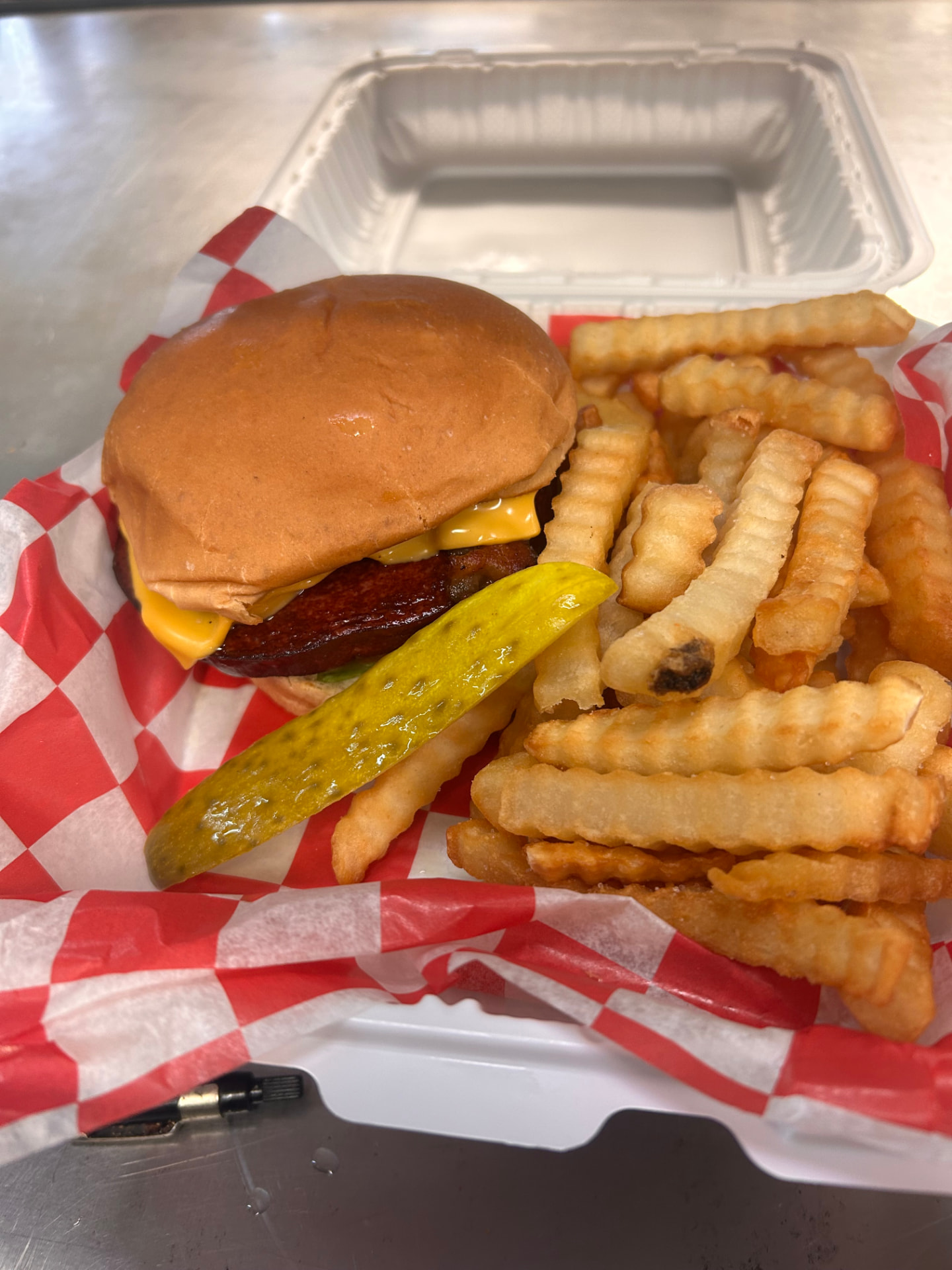 Bacon cheeseburger with crinkle-cut fries and a pickle